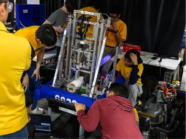 People huddled, working on an FRC robot machine